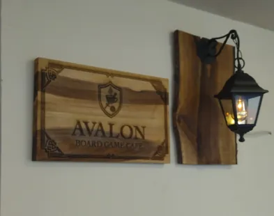 Монтирана дървена табела и стенен фенер върху дървен панел в кафе Avalon във Варна.
